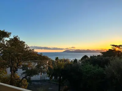 a view of the ocean at sunset from a balcony at Appartement - villa Le Saint Georges avec superbe jardin et vue mer panoramique in Cannes