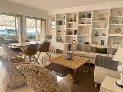 a living room with a couch and a table and chairs at Appartement - villa Le Saint Georges avec superbe jardin et vue mer panoramique in Cannes