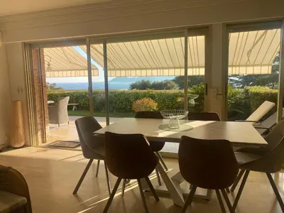a dining room with a table and chairs and a large window at Appartement - villa Le Saint Georges avec superbe jardin et vue mer panoramique in Cannes