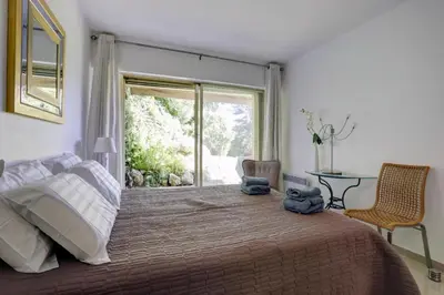 a bedroom with a large bed with a large window at Appartement - villa Le Saint Georges avec superbe jardin et vue mer panoramique in Cannes