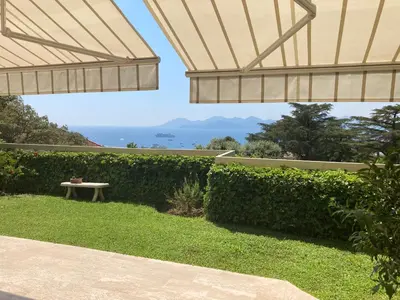 a view from the garden of a house with a bench at Appartement - villa Le Saint Georges avec superbe jardin et vue mer panoramique in Cannes