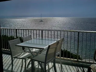 a table and chairs on a balcony overlooking the water at Fettolina Palm Beach, Location Cannes front de mer et plage in Cannes