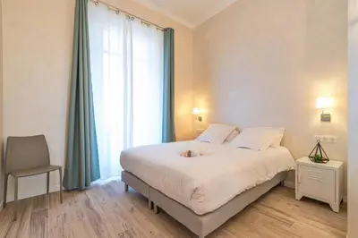 a bedroom with a bed and a chair and a window at Résidence Montaigne - Luxurious - 350m Palais - LRA Cannes in Cannes