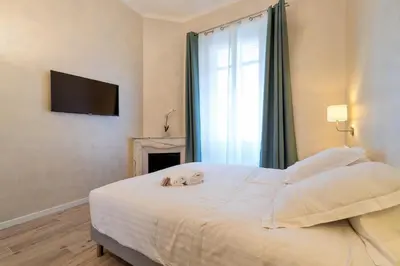 a bedroom with a large white bed with a fireplace at Résidence Montaigne - Luxurious - 350m Palais - LRA Cannes in Cannes