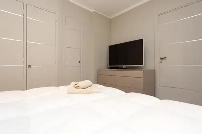 a white bedroom with a bed and a flat screen tv at 24 Août Sucquet in Cannes