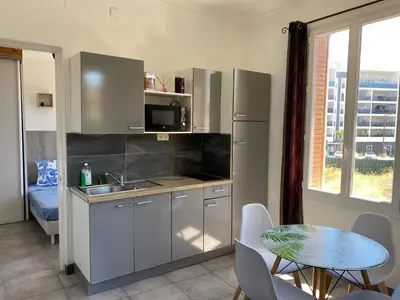 a kitchen with a sink and a table with chairs at Appartement PALOMA Proche Cannes in Le Cannet