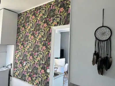 a room with a wall with a floral wallpaper at Appartement PALOMA Proche Cannes in Le Cannet