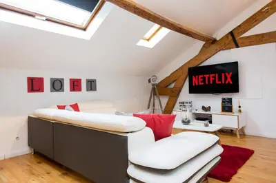 a attic living room with a white couch and red pillows at LB Vacation Rentals I Big Loft 107m2, 10min Walk to Palais des Festivals in Cannes