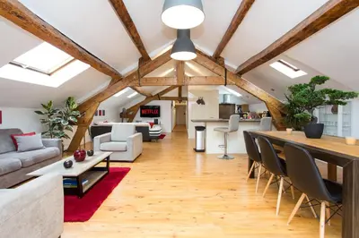 a living room with wooden ceilings and a table with chairs at LB Vacation Rentals I Big Loft 107m2, 10min Walk to Palais des Festivals in Cannes