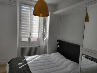 a bedroom with a bed and a window with shutters at Cosy apartment in Cannes