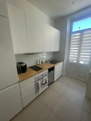 a kitchen with white cabinets and a sink and a stove at Cosy apartment in Cannes