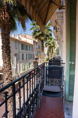 a balcony with a chair and palm trees and buildings at Central Cannes, 200m to Palais, walk everywhere in Cannes