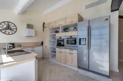 a kitchen with a stainless steel refrigerator and wooden cabinets at Residence Provencal - Luxurious - 300m Palais - LRA CANNES in Cannes