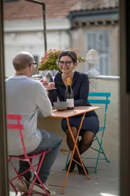 a man and a woman sitting at a table with a bottle of wine at Belle surprise cœur de ville, cosy avec terrasse in Cannes