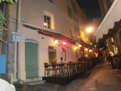 a restaurant with tables and chairs on a street at night at Studio Suquet Saint Antoine in Cannes