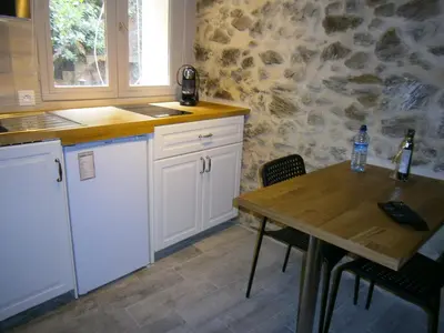 a kitchen with a table and a stone wall at Studio Suquet Saint Antoine in Cannes