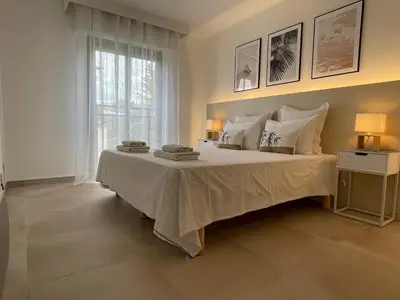 a bedroom with a large white bed with a window at Domaine D'Ahmosis, modern 2 bedrooms refurbished apartment, f3 moderne fraichement rénové in Le Cannet