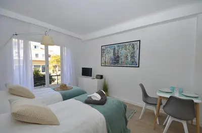 a hotel room with two beds and a desk and a window at 9 Rue Buttura in Cannes