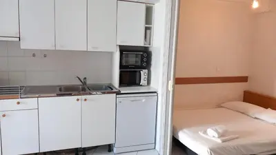 a small kitchen with white cabinets and a bed at Calm Flat in Cannes