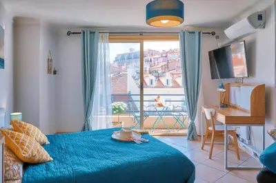 a bedroom with a blue bed and a large window at Grand Studio Cannes Centre in Cannes
