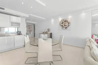 a white kitchen with a glass table and chairs at REF 1181 - Cannes Croisette - Sea view apartment for rent in Cannes