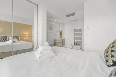 a white bedroom with two beds and a mirror at REF 1181 - Cannes Croisette - Sea view apartment for rent in Cannes