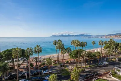 a view of the beach and palm trees at REF 1181 - Cannes Croisette - Sea view apartment for rent in Cannes