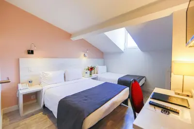 a hotel room with a bed and a desk and a bed at Hotel Cannes Croisette in Cannes