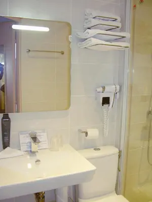 a bathroom with a sink and a toilet and a mirror at Hotel Cannes Croisette in Cannes
