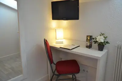 a desk with a red chair and a television on a wall at Hotel Cannes Croisette in Cannes