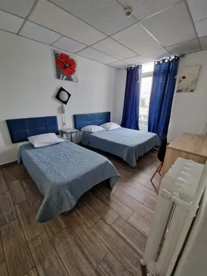 a hotel room with two beds and a window at Hôtel du Nord in Cannes