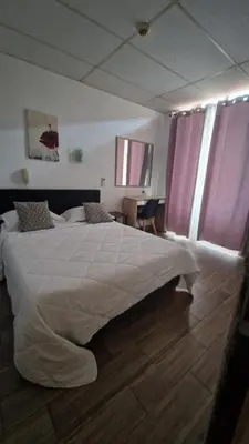 a bedroom with a large white bed with purple curtains at Hôtel du Nord in Cannes