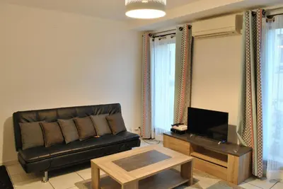 a living room with a black leather couch and a table at Centre Riviera 2P LHO5516 in Cannes