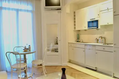 a kitchen with white cabinets and a table and chairs at Palais Hoche 2P LON5218 in Cannes