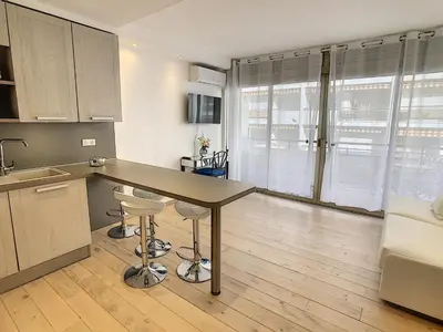 a kitchen with a table and stools in a room at Grand studio cabine à côté des plages NER634 in Cannes