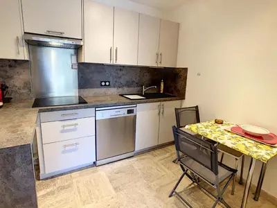 a kitchen with white cabinets and a table with chairs at Le Windsor 2P DET2002 in Cannes