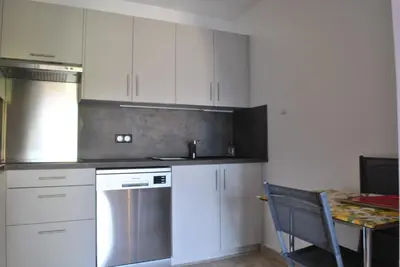 a kitchen with white cabinets and a table with a chair at Le Windsor 2P DET2002 in Cannes