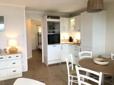 a kitchen with white cabinets and a table and chairs at T2 superbe vue mer Cannes in Cannes
