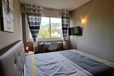 a bedroom with a bed and a window and a desk at 4-Room Apartment with Terrace & Sea View 5-Minute Walk to the Beach in Cannes