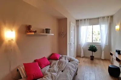 a living room with a couch with pink pillows at 4-Room Apartment with Terrace & Sea View 5-Minute Walk to the Beach in Cannes