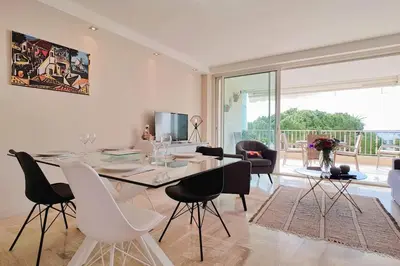 a white dining room with a table and chairs at 4-Room Apartment with Terrace & Sea View 5-Minute Walk to the Beach in Cannes