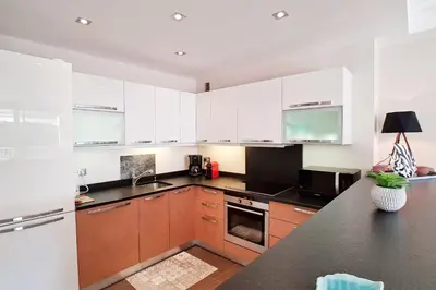 a kitchen with white cabinets and a black counter top at 4-Room Apartment with Terrace & Sea View 5-Minute Walk to the Beach in Cannes