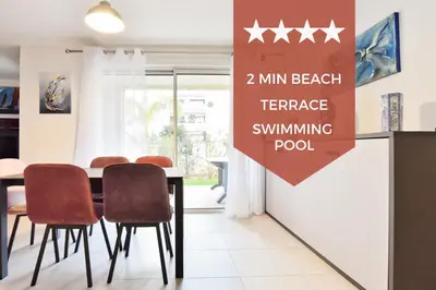 a dining room with a table with chairs and a sign that reads min beach at 2-Br with Terrace and Pool in the Heart of Palm Beach in Cannes