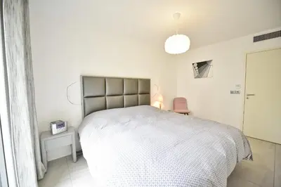 a bedroom with a white bed and a pink chair at 2-Br with Terrace and Pool in the Heart of Palm Beach in Cannes