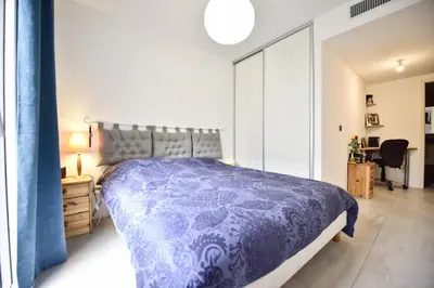 a bedroom with a bed with a blue comforter at 2-Br with Terrace and Pool in the Heart of Palm Beach in Cannes
