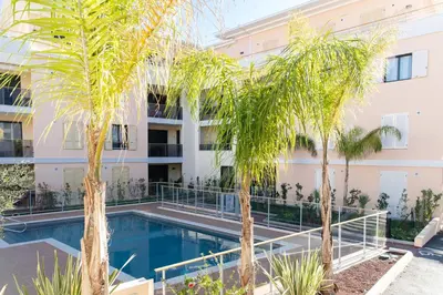 a swimming pool in front of a building with palm trees at 2-Br with Terrace and Pool in the Heart of Palm Beach in Cannes