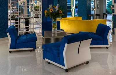 a lobby with blue chairs and a table with a vase of flowers at Juliana Hotel Cannes in Cannes