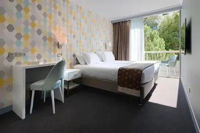 a bedroom with a bed and a desk and a window at Juliana Hotel Cannes in Cannes