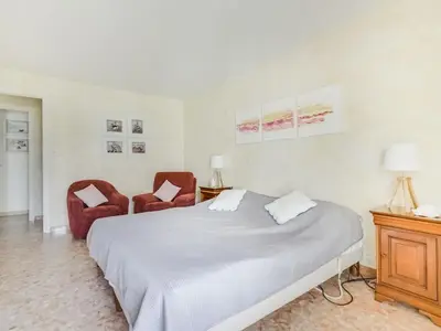 a bedroom with a large bed and two chairs at Apartment Reine Astrid-3 by Interhome in Cannes