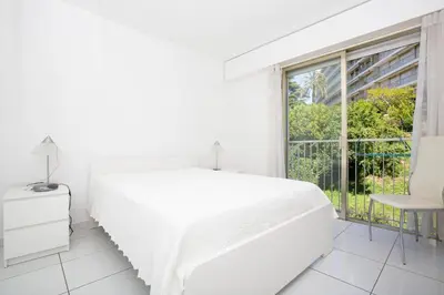 a white bedroom with a white bed and a window at Appartement vacances cannes in Cannes